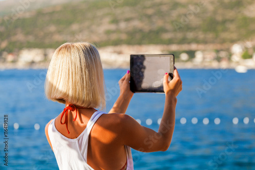 Young girl makes selfie photos with a tablet in the sea in summer. Summer vacation at sea. Dubrovnik. Croatia © LALSSTOCK