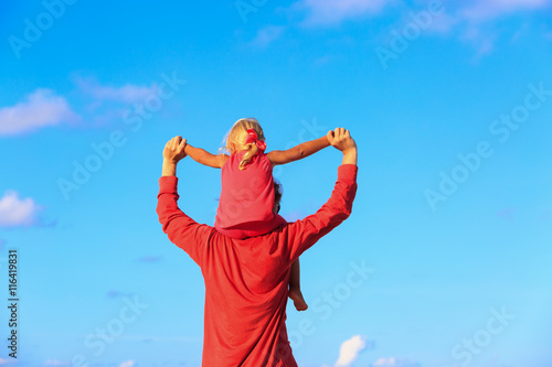 father and little daughter on shoulders play at sky