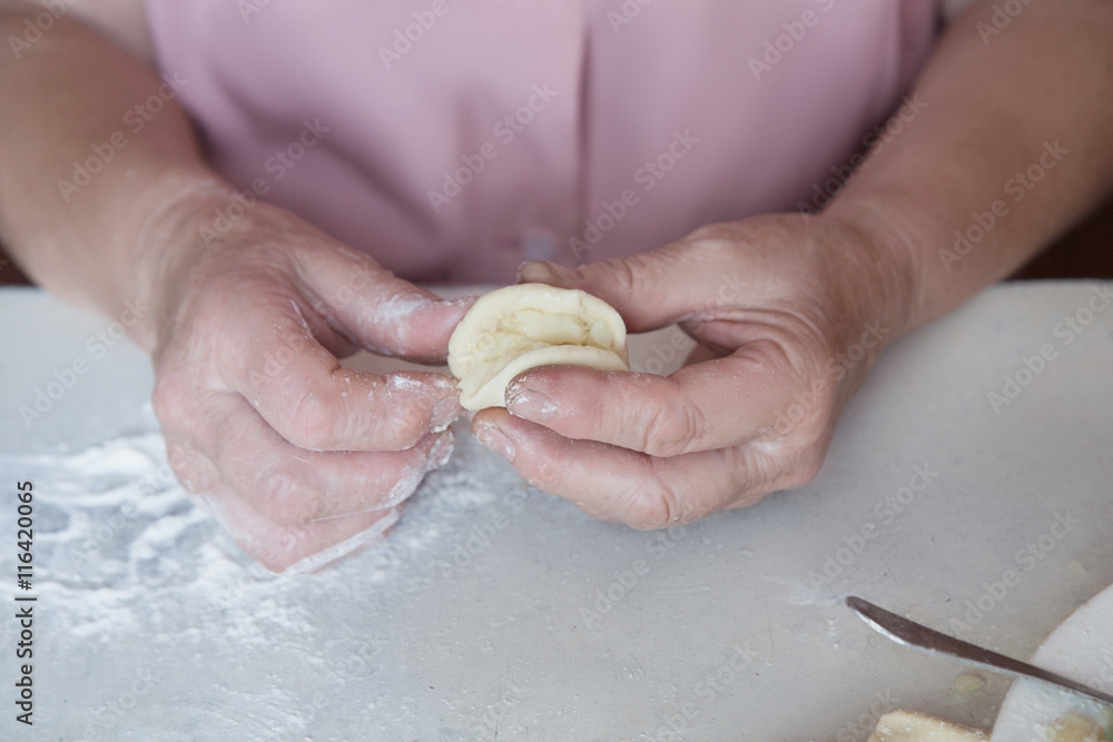 hands of an elderly woman mold dumplings stuffed