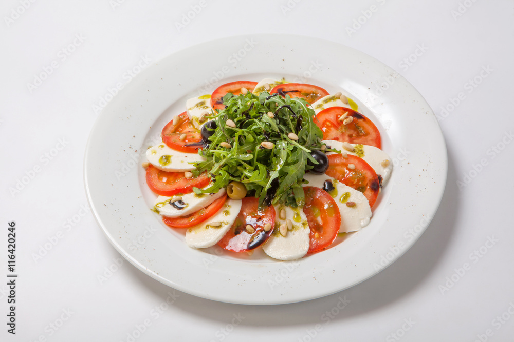 Caprese salad. Fresh salad with fresh juicy tomatoes with mozzarella cheese and fresh arugula tossed with balsamic vinegar and pine nuts Caprese salad. Fresh salad with fresh juicy tomatoes with mozzarella cheese and fresh arugula tossed with balsamic vinegar and pine nuts