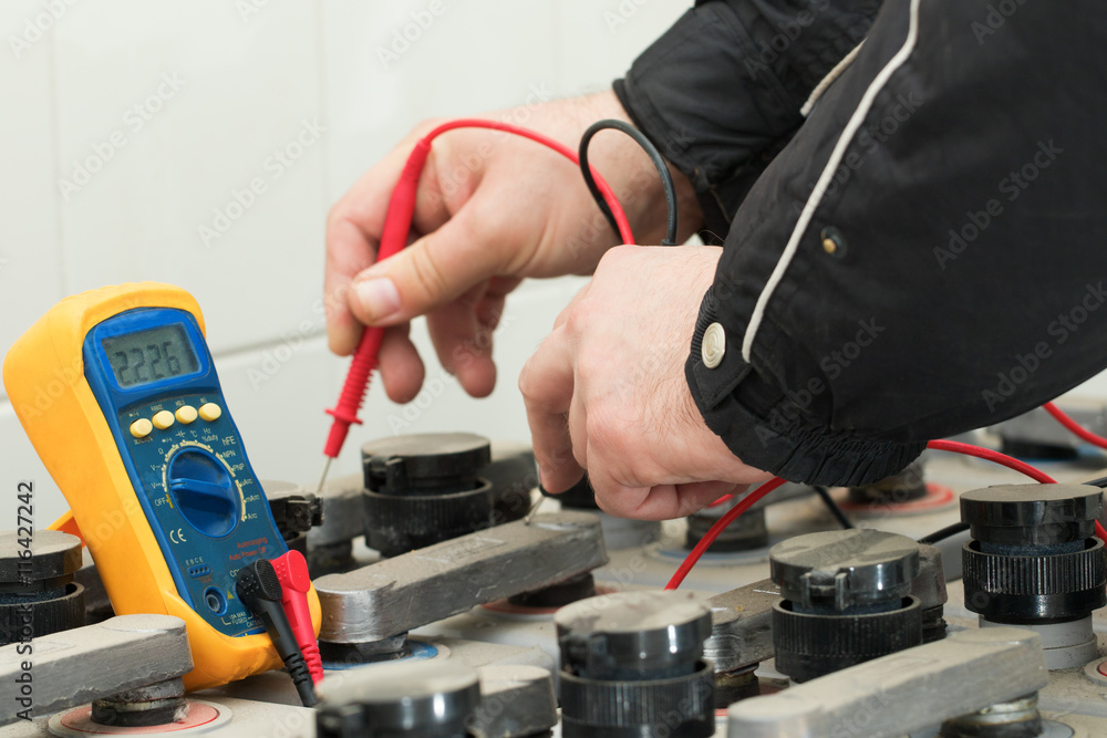 Electrician check battery with yellow multimeter Electrician check battery with yellow multimeter