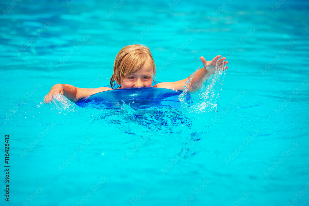 Happy little boy playing in swimming pool on a hot summer day