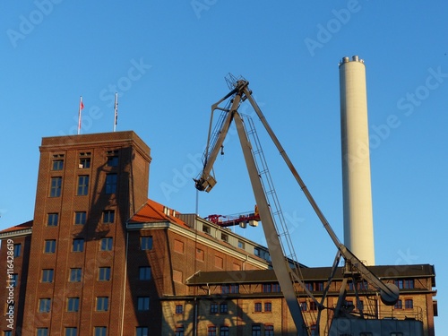 Flechtheimspeicher und Rhenusspeicher aus rotbraunem Backstein, alter Hafenkran und Schornstein des Kraftwerk vor blauem Himmel am Hafen am Dortmund-Ems-Kanal in Münster in Westfalen im Münsterland photo