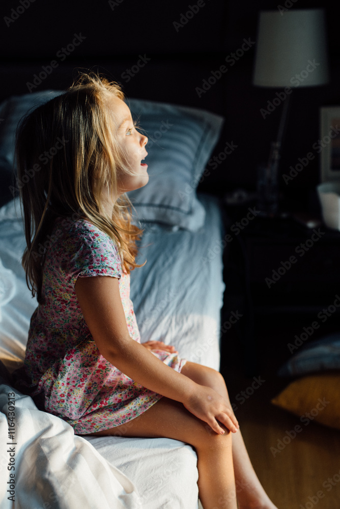 Girl sitting on edge of bed, looking away Girl sitting on edge of bed, looking away