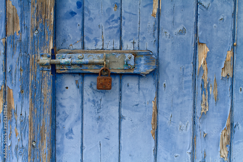 Flaking blue painted wooden door with rusty padlock