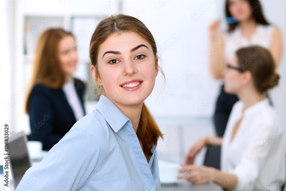 Portrait of a young business woman against a group of business people at  meeting.