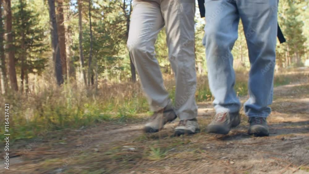 A man and a woman walking on forest trail, close up of legs A man and a woman walking on forest trail, close up of legs