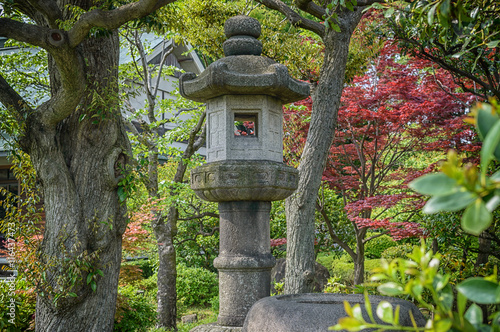 a stone lantern with red maple leaves as background