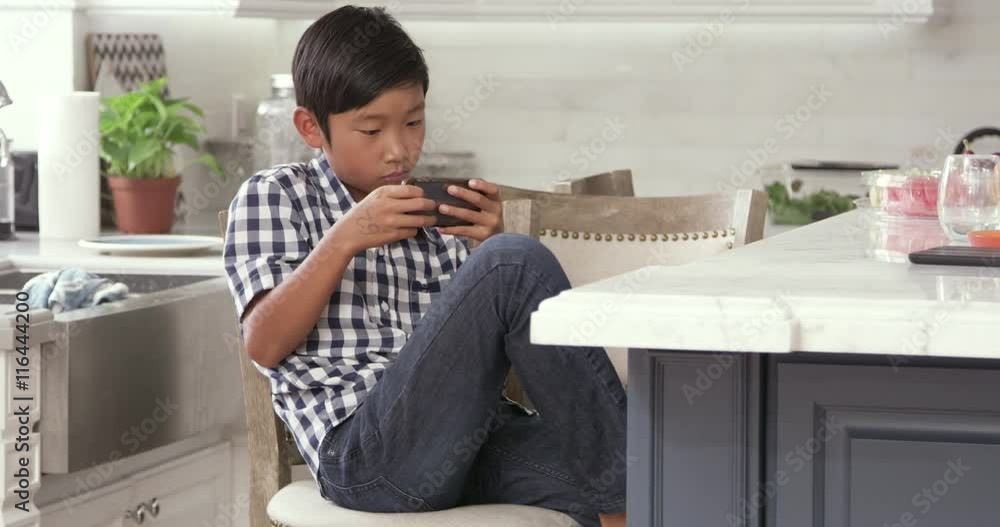Young Asian Boy Playing Game On Mobile Device Young Asian Boy Playing Game On Mobile Device