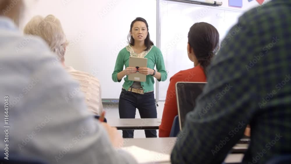 Female Asian teacher with tablet takes adult education class