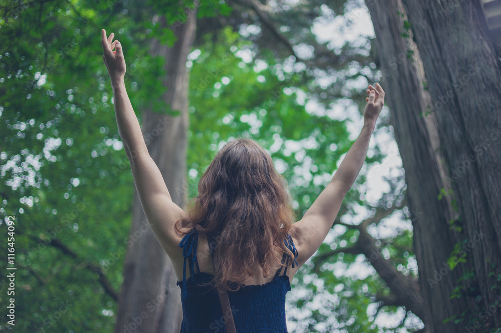 Woman raising her arms in the forest Woman raising her arms in the forest