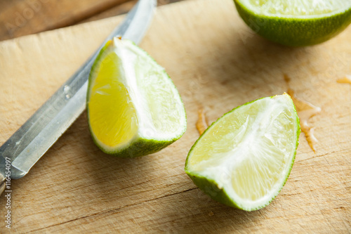 Fresh cut limes on wooden cutting board. Selective focus. Blurred background.