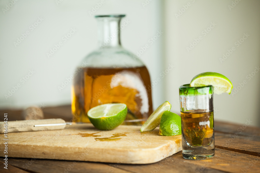 Shot glass of tequila with bottle. Selective focus. Blurred background. Shot glass of tequila with bottle. Selective focus. Blurred background.