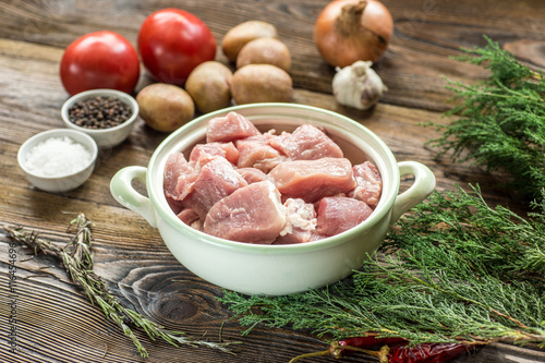 Raw pork ham with vegetables and spices on a wooden cutting boar