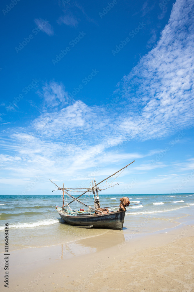 Old fishing boat and deep bluesky background at Hua Hin beach, Prachuap Khiri Khan Province, Thailand.