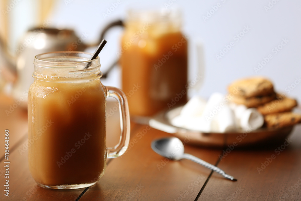 Iced coffee in glass jar with straw on brown wooden table Iced coffee in glass jar with straw on brown wooden table