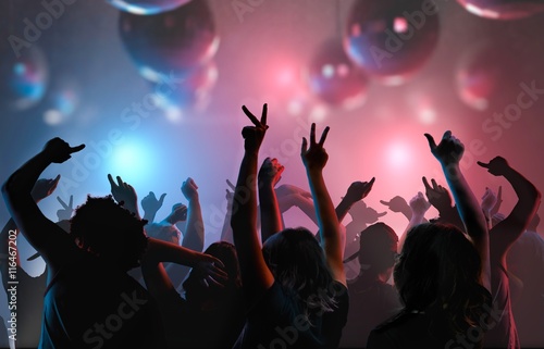 Nightlife and disco concept. Silhouettes of young people are enjoying and dancing in club.