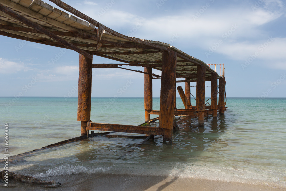 Old rusty pier in quiet summer sea