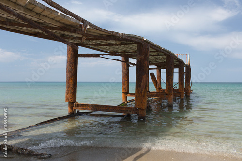 Old rusty pier in quiet summer sea