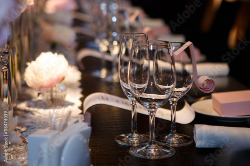 Banquet table, glasses and plates, forks and knives, napkins and buttons for a luxurious celebration in anticipation of guests. Luxury festive table.  photo