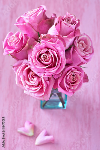 Beautiful fresh roses flowers in a vase on a pink background.