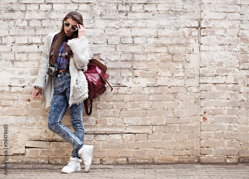 Young street fashion girl on the background of old brick wall. Outdoors, lifestyle.