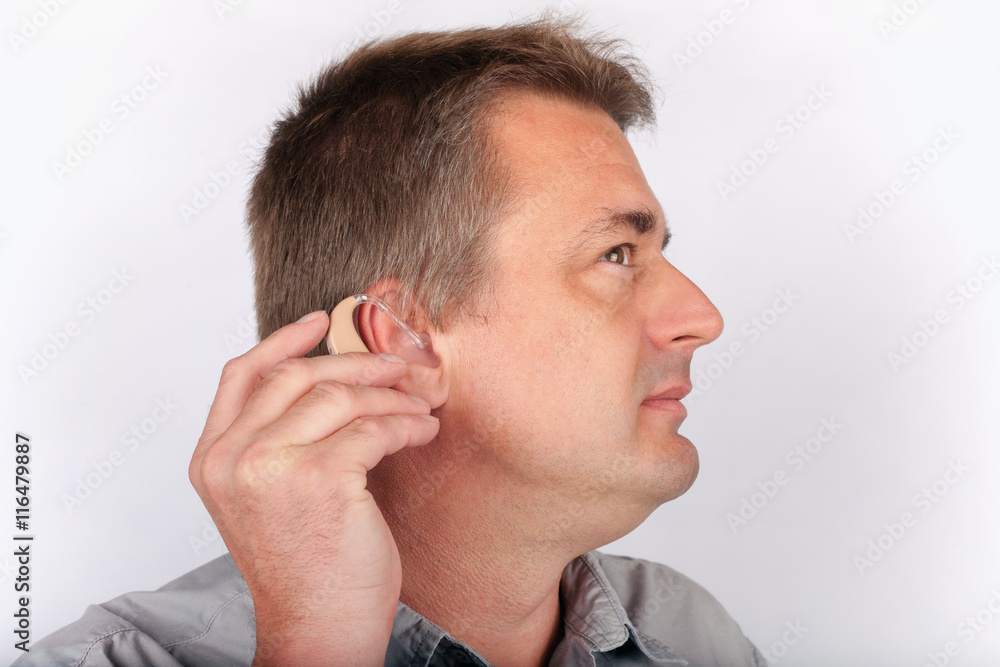 Fototapeta premium Senior inserting hearing aid into ear