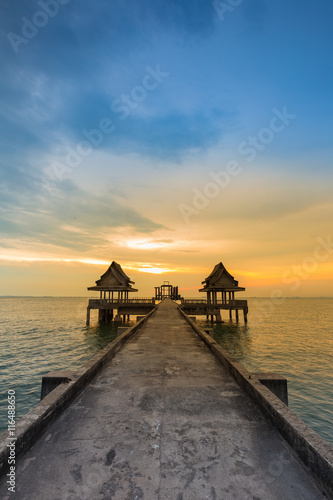 Walking way leading to lonely temple in ocean with beautiful natural sunset sky background photo