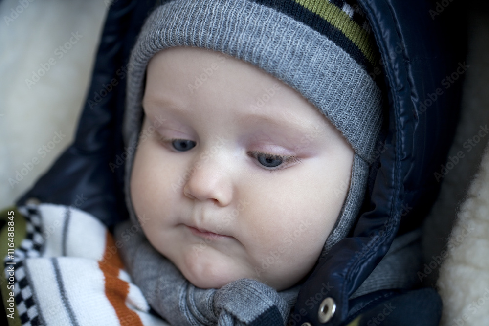 Infant boy is lying in a stroller in winter clothes Infant boy is lying in a stroller in winter clothes