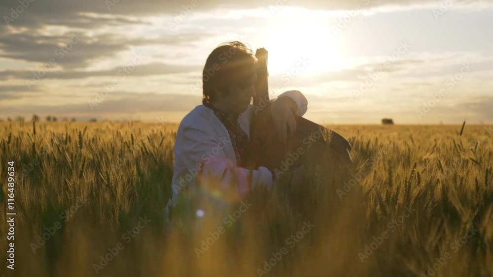 Young man playing pandora in wheat field at sunset. Young man playing pandora in wheat field at sunset.