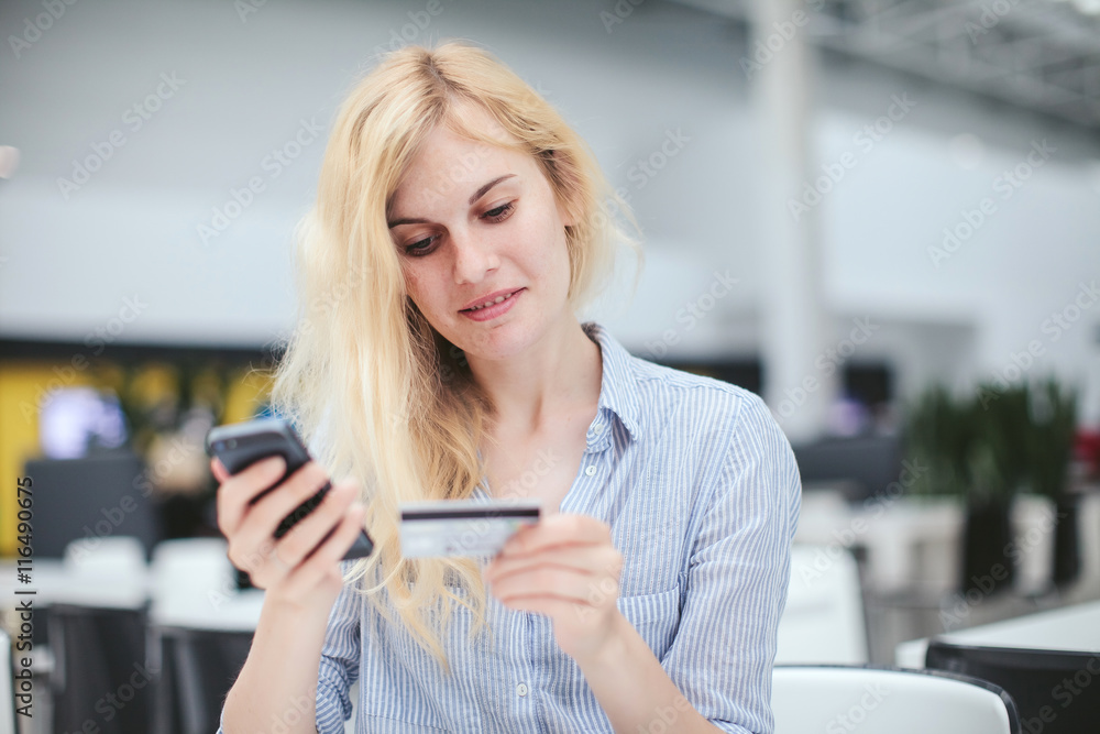 Beautiful woman using smartphone shopping online with credit card at shopping center, business center