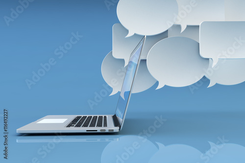 Communication technology, social networking, internet and online messaging concept, white empty speech bubbles and modern laptop computer on blue background with reflection