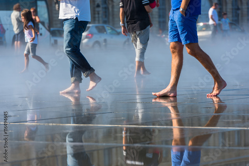 People having fun in a mirror fountain in Bordeaux, France photo