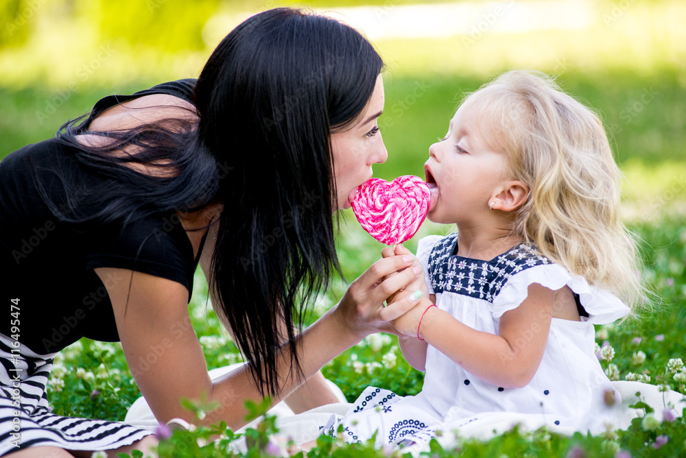 mother and daughter eating candy on a stick mother and daughter eating candy on a stick