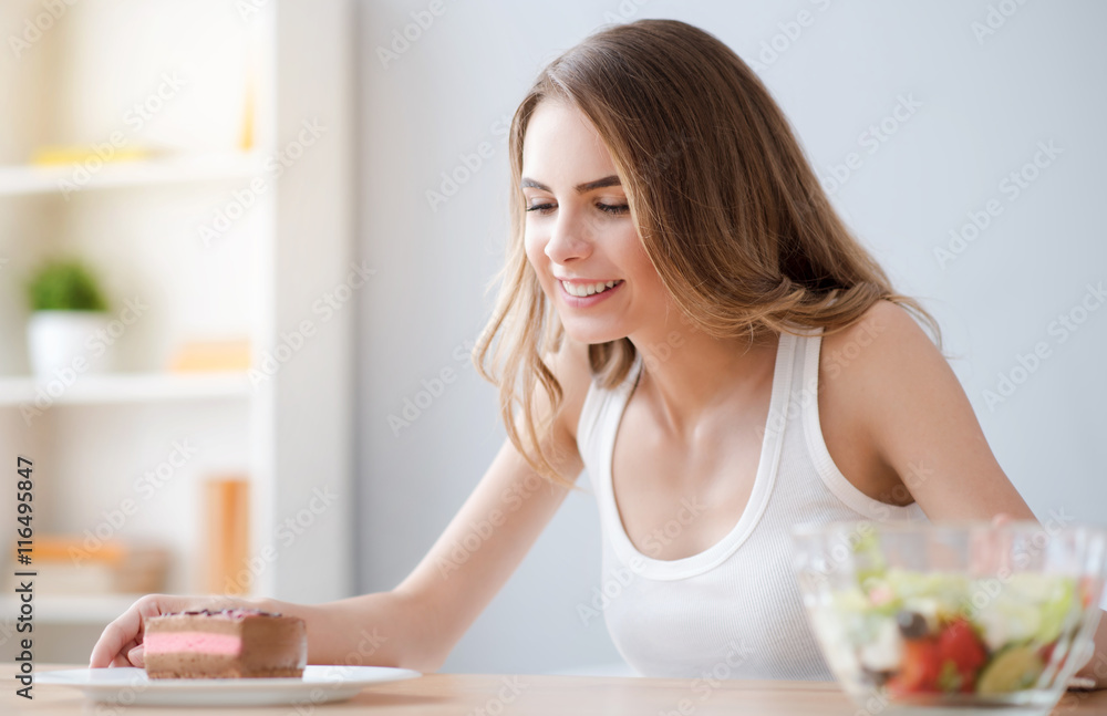 Positive woman looking at piece of cake