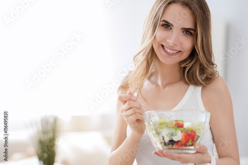 Cheerful woman eating vegetable salad.
