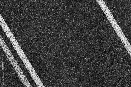 Level asphalted road with a dividing white stripes. The texture of the tarmac, top view.
