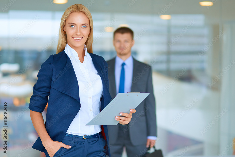 Portrait of young businesswoman in office with colleagues in the background Portrait of young businesswoman in office with colleagues in the background