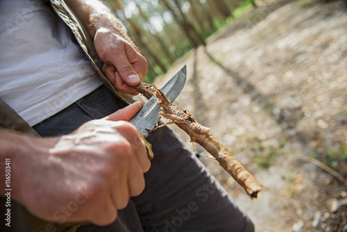 Young tourist cutting wood in nature