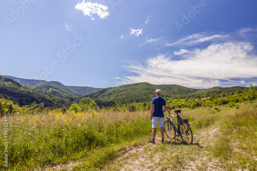 Young man standing near  bicycle in morning sunrise with wonderf photo