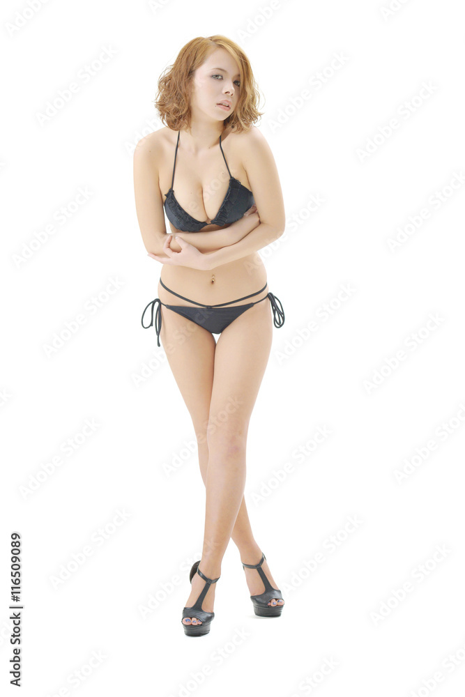 金髪の女性モデルが、黒いビキニの水着を着て立っています。この画像はスタジオで撮影されて物で、背景は白バックです。