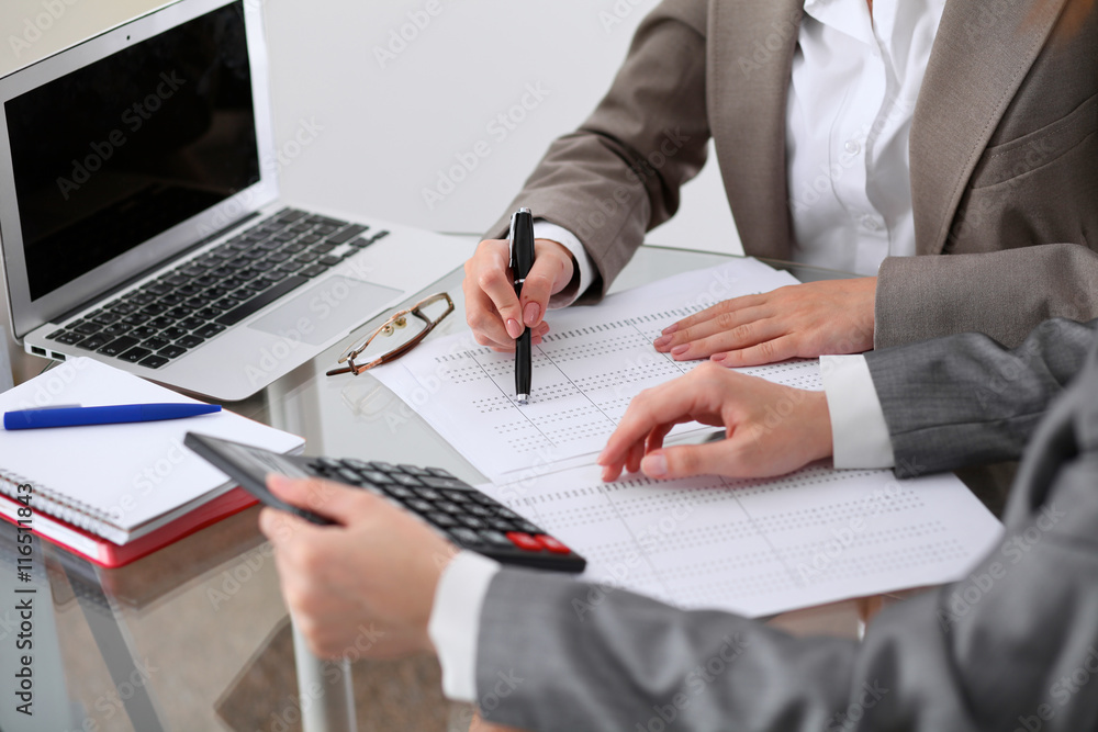 Two female accountants counting on calculator income for tax form completion hands closeup. Internal Revenue Service inspector checking financial document. Planning budget, audit concept Two female accountants counting on calculator income for tax form completion hands closeup. Internal Revenue Service inspector checking financial document. Planning budget, audit concept