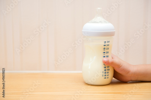 kid getting a baby bottle of powdered milk without lid at home photo