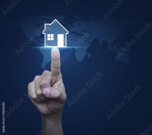 Hand pressing house icon with copy space over digital world map