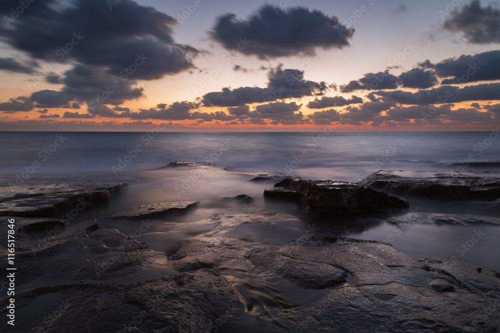 Long exposure creating dreamy silky water effect on the rocks after sunset, Nahariya Beach