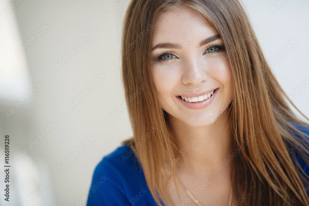 Beautiful young woman brunette with long straight hair,pretty smile,white straight teeth,wearing a blue summer dress,wears a gold chain on the neck,posing on light gray background Beautiful young woman brunette with long straight hair,pretty smile,white straight teeth,wearing a blue summer dress,wears a gold chain on the neck,posing on light gray background