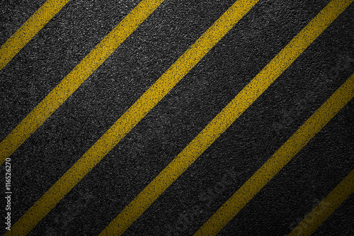 Level asphalted road with a dividing yellow stripes. The texture of the tarmac, top view.