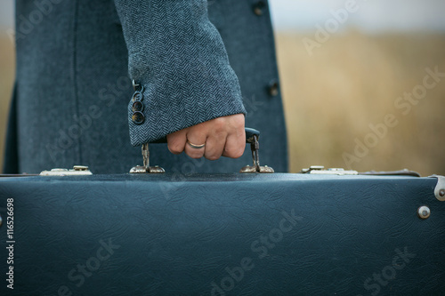 Tableau sur toile man in woolen overcoat holds an old suitcase, retro