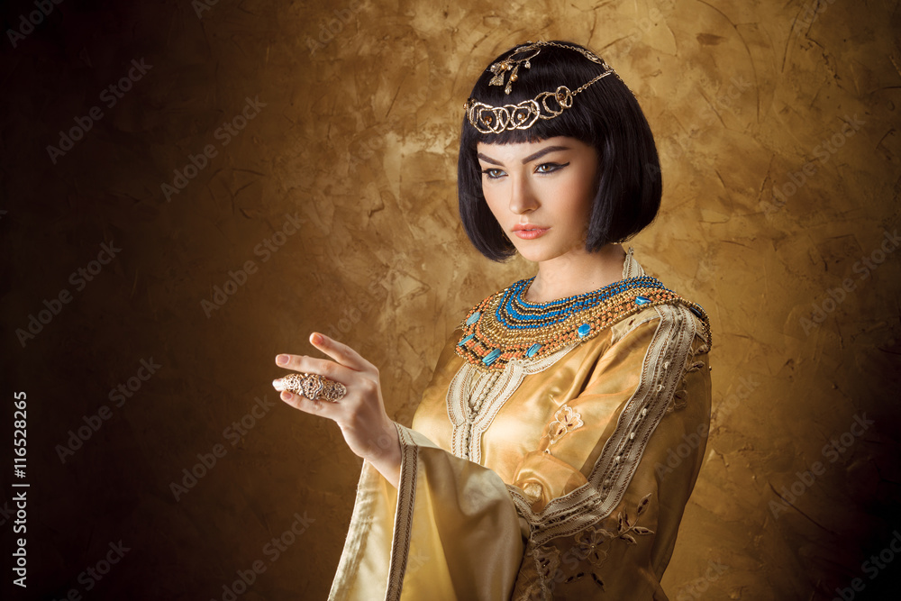 Beautiful Egyptian woman like Cleopatra pointing finger away on golden ...
