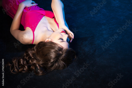 Sensual model in pink dress posing on floor with eyes closed